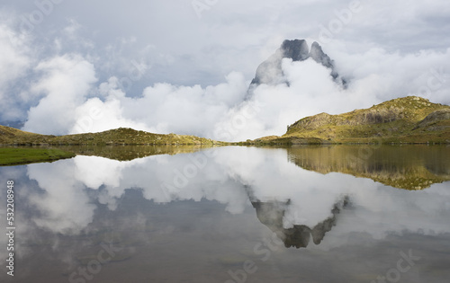 Sunset with the Midi dOssau mountain in the clouds reflected on the Ayous lakes, Pyrenees National Park, France. photo