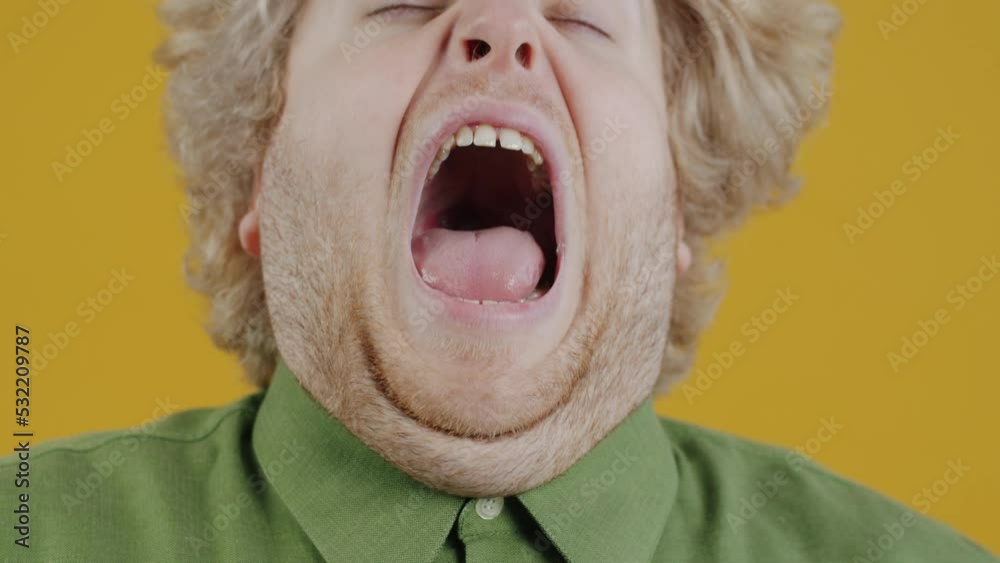 Close-up portrait of sick young man sneezing then looking at camera on yellow color background. People and health problems concept.