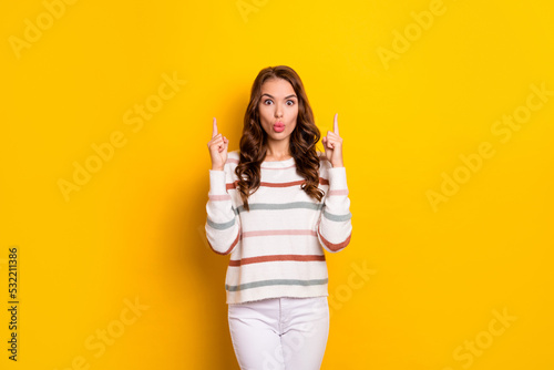 Photo of pretty impressed girl pouted lips direct fingers up empty space isolated on yellow color background