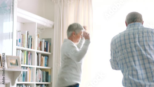 Happy senior couple dance in their living room together, acting silly and smiling in love while retired. Happily married healthy elderly people, having fun dancing in retirement and being goofy alone photo