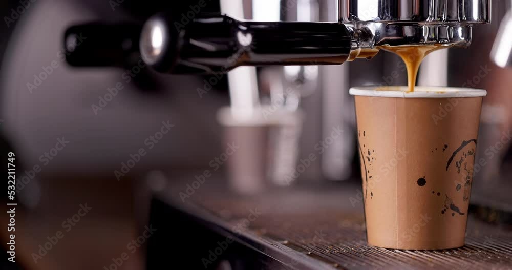 Coffee machine filling a cup with hot black espresso with foam. Barista make coffee with professional coffee machine. 