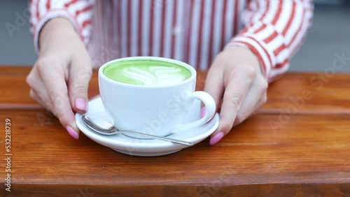 woman puts a cup of matcha latte in a coffee shop outside photo