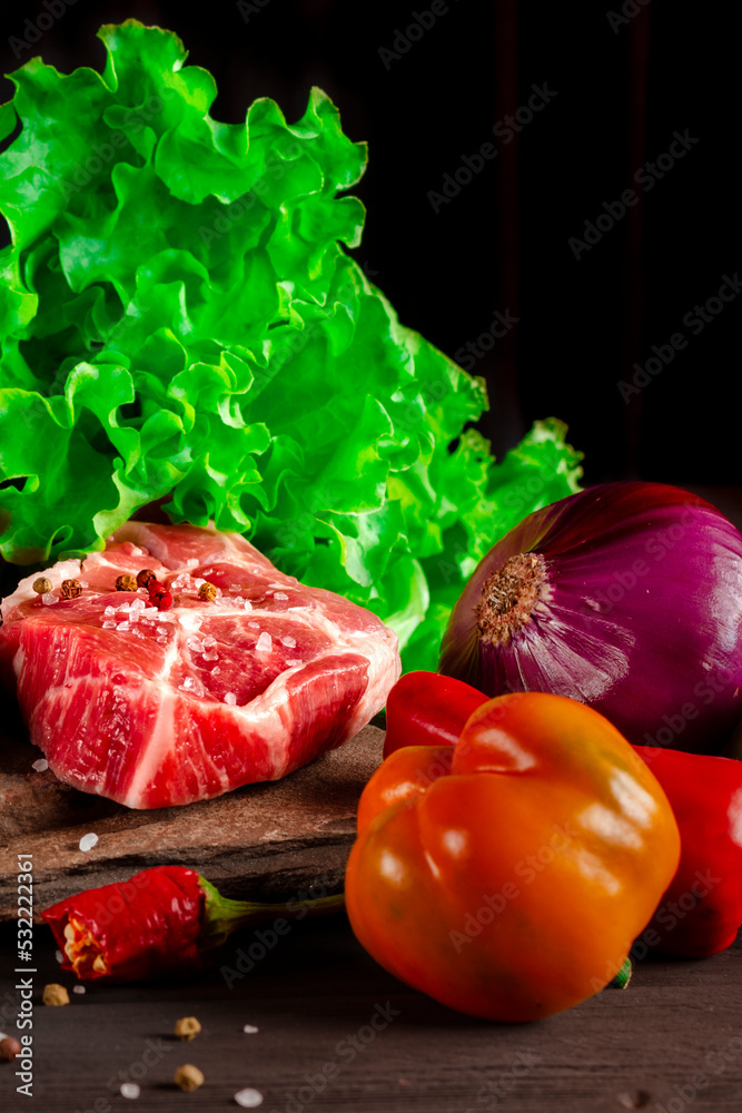 Raw juicy pork steaks and fresh vegetables before cooking