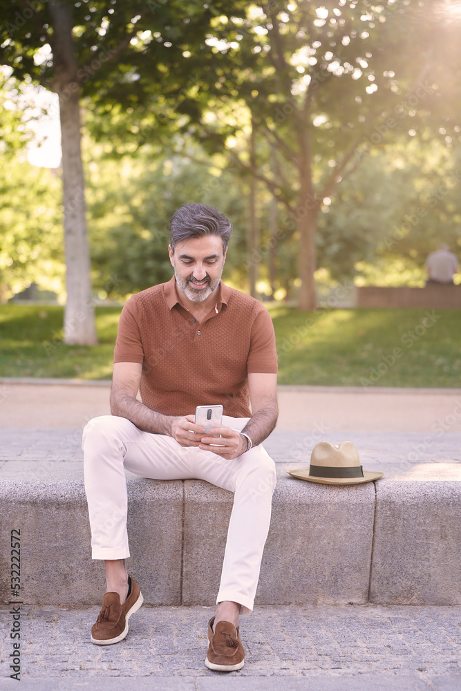 Obraz premium Man relaxing while using a mobile phone outdoors in a park. Technology concept.