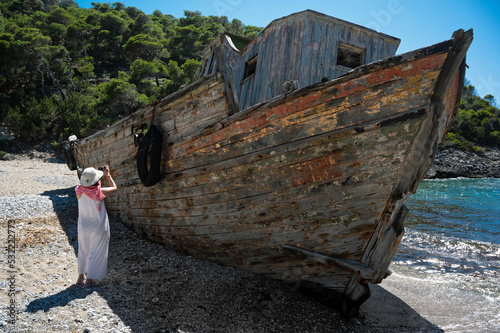 A tourist takes a picture of a shipwreck abandoned at a sea-coast of Skyros island in Greece photo