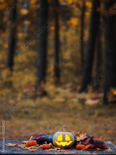 Carved smiling pumpkin lantern on a wooden table in the autumn forest