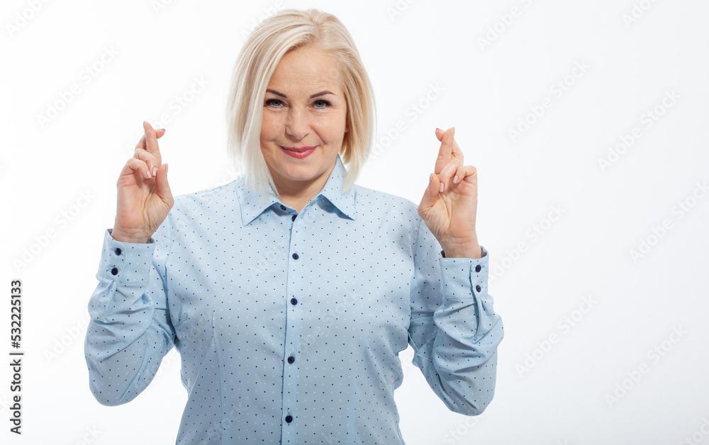 Half-length portrait of beautiful dreamy blonde wearing blue classic blouse standing crossing her fingers with open eyes wanted to make her wishes come true. Isolated on white. Half-length portrait of beautiful dreamy blonde wearing blue classic blouse standing crossing her fingers with open eyes wanted to make her wishes come true. Isolated on white.