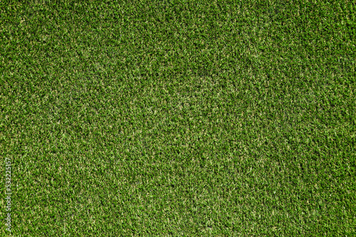 Background, texture of green artificial grass on a meadow for playing football, baseball, soccer, golf.