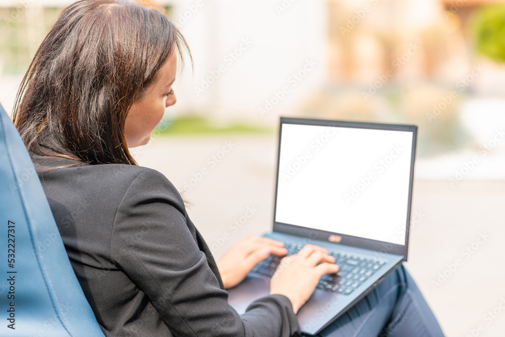 Blank white screen.Mockup.Young brunette business woman use laptop computer outdoor cafe.She dressed in black suit spending her lunch time at street cafe terrace.Close-up.Selective focus. Blank white screen.Mockup.Young brunette business woman use laptop computer outdoor cafe.She dressed in black suit spending her lunch time at street cafe terrace.Close-up.Selective focus.