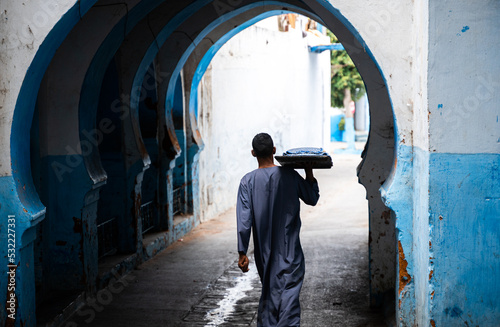 Foto Hombre árabe portando comida diaria pasando por arco musulmán .