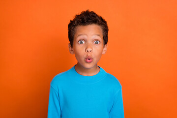 Photo of astonished boy dressed blue trendy pullover reaction cool toy shop low prices isolated on orange color background