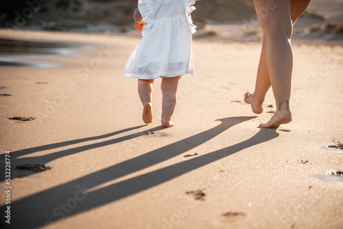 Madre e hija caminando por la playa. photo