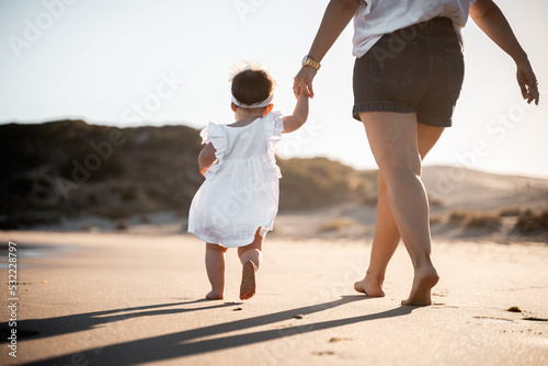 Madre e hija caminando por la orilla de la playa.  photo