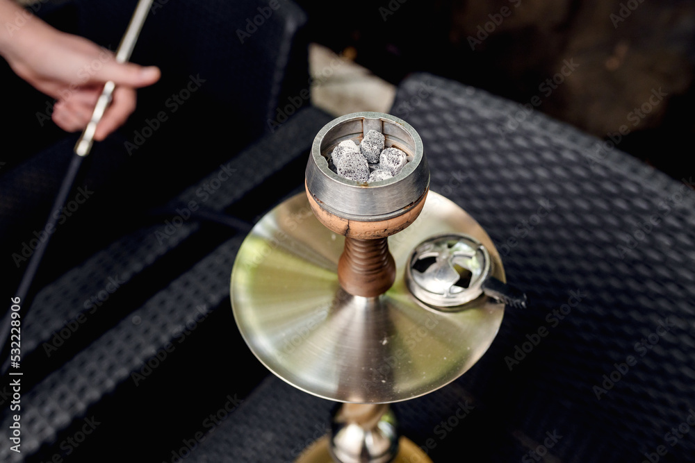 Hookah bowl with tobacco, heating device and coconut coal in hookah lounge. Hookah bowl with tobacco, heating device and coconut coal in hookah lounge.