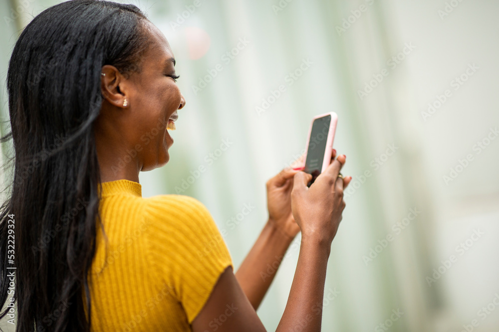 Black woman laughing while using mobile phone Black woman laughing while using mobile phone