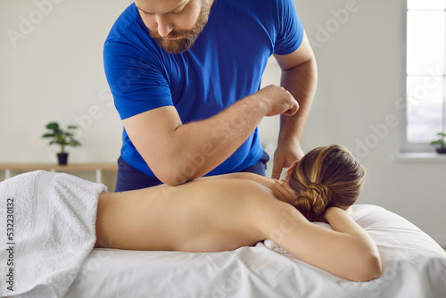 Medical assistance for body. Massage therapist doing massotherapy with elbow on back of young woman lying on massage table. Male masseur doctor doing osteopathic relaxing massage to young woman.