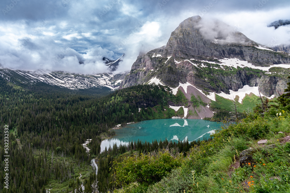 Grinnell Lake in Glacier National Park on a cloudy summer day, with dramatic clouds