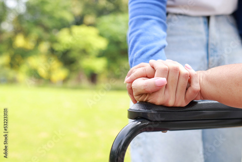 A caregiver shakes hands of an elderly person sitting on a wheelchair. Nursing concepts to take care of elderly health care, senior health rehabilitation center. child taking care of old mother