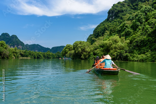 Tourists sitting on rowing boats enjoy the beautiful scenery of rivers and mountains in Trang An, Ninh Binh province, Vietnam.