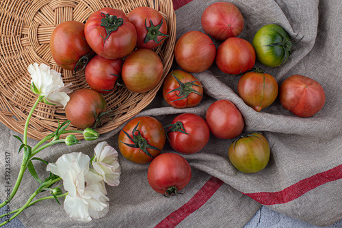 fresh red tomato on wicker basket on gray background.
