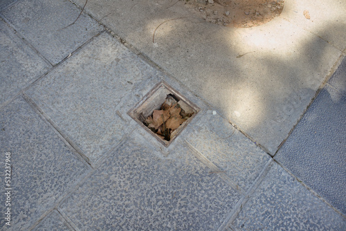 A badly covered or broken trap on a sidewalk of a walk in a city
