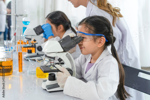 kids studying science in laboratory with a female scientist as a mentor is teaching the students