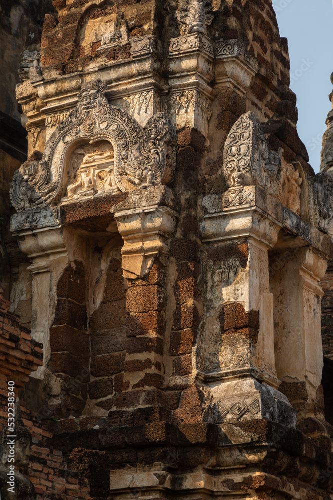 Decorative elements and reliefs in Wat Mahathat temple and pagodas of Thai style architecture and trees, in Sukhothai Historical Park at sunset