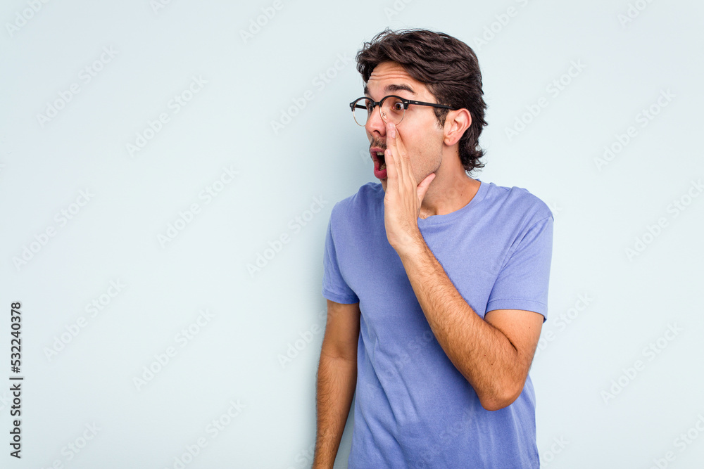 Young hispanic man isolated on blue background being shocked because of something she has seen. Young hispanic man isolated on blue background being shocked because of something she has seen.