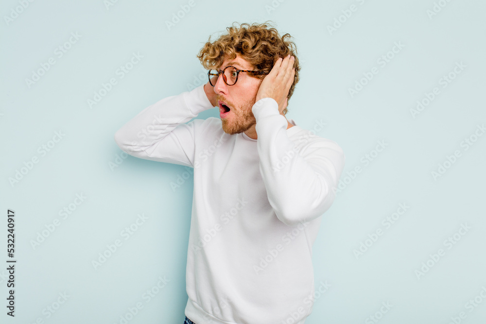Young caucasian man isolated on blue background screaming, very excited, passionate, satisfied with something. Young caucasian man isolated on blue background screaming, very excited, passionate, satisfied with something.