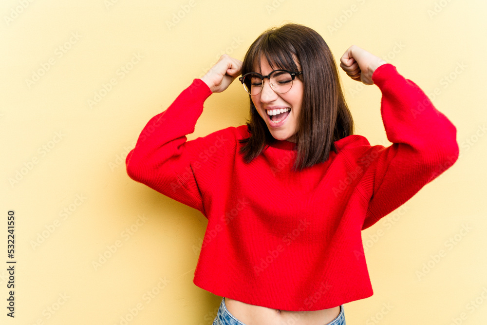 Young caucasian woman isolated on yellow background raising fist after a victory, winner concept. Young caucasian woman isolated on yellow background raising fist after a victory, winner concept.