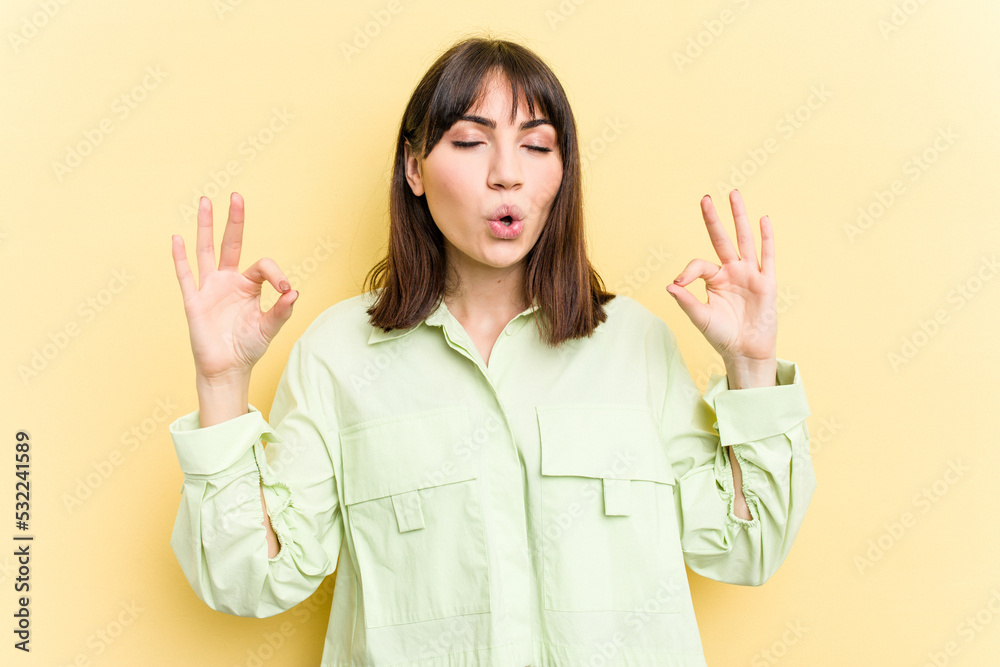 Young caucasian woman isolated on yellow background relaxes after hard working day, she is performing yoga.