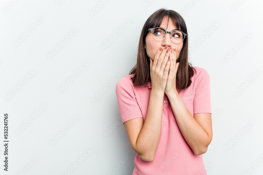 Young caucasian woman isolated on white background thoughtful looking to a copy space covering mouth with hand. Young caucasian woman isolated on white background thoughtful looking to a copy space covering mouth with hand.