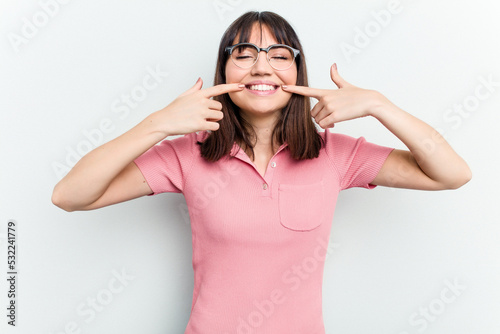 Young caucasian woman isolated on white background smiles  pointing fingers at mouth.