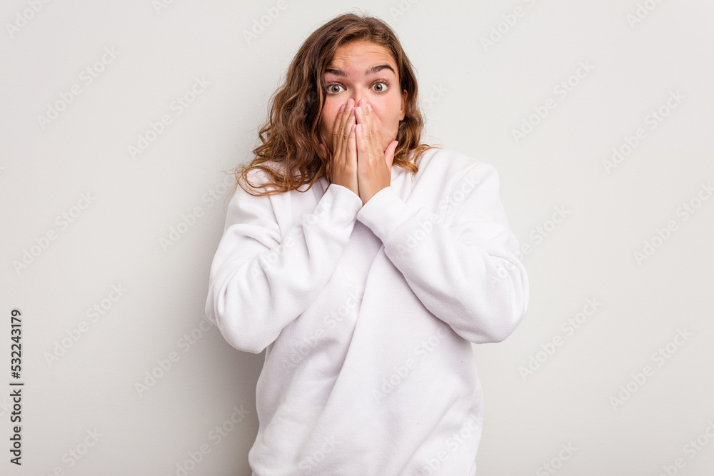 Young caucasian woman isolated on blue background covering mouth with hands looking worried.