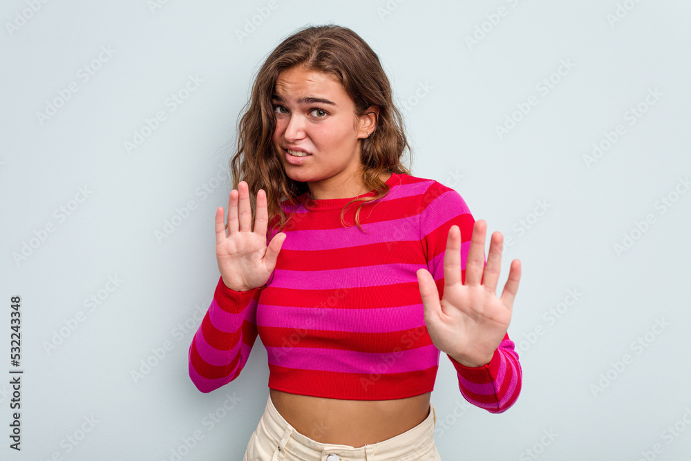 Young caucasian woman isolated on blue background rejecting someone showing a gesture of disgust. Young caucasian woman isolated on blue background rejecting someone showing a gesture of disgust.