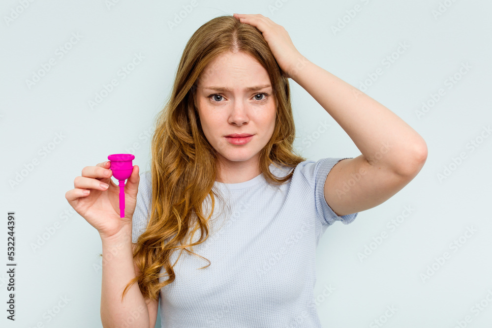 Young caucasian woman holding menstrual cup isolated on blue background being shocked, she has remembered important meeting. Young caucasian woman holding menstrual cup isolated on blue background being shocked, she has remembered important meeting.