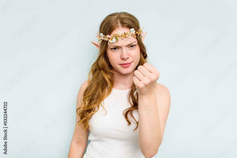 Young elf woman isolated on blue background showing fist to camera, aggressive facial expression. Young elf woman isolated on blue background showing fist to camera, aggressive facial expression.
