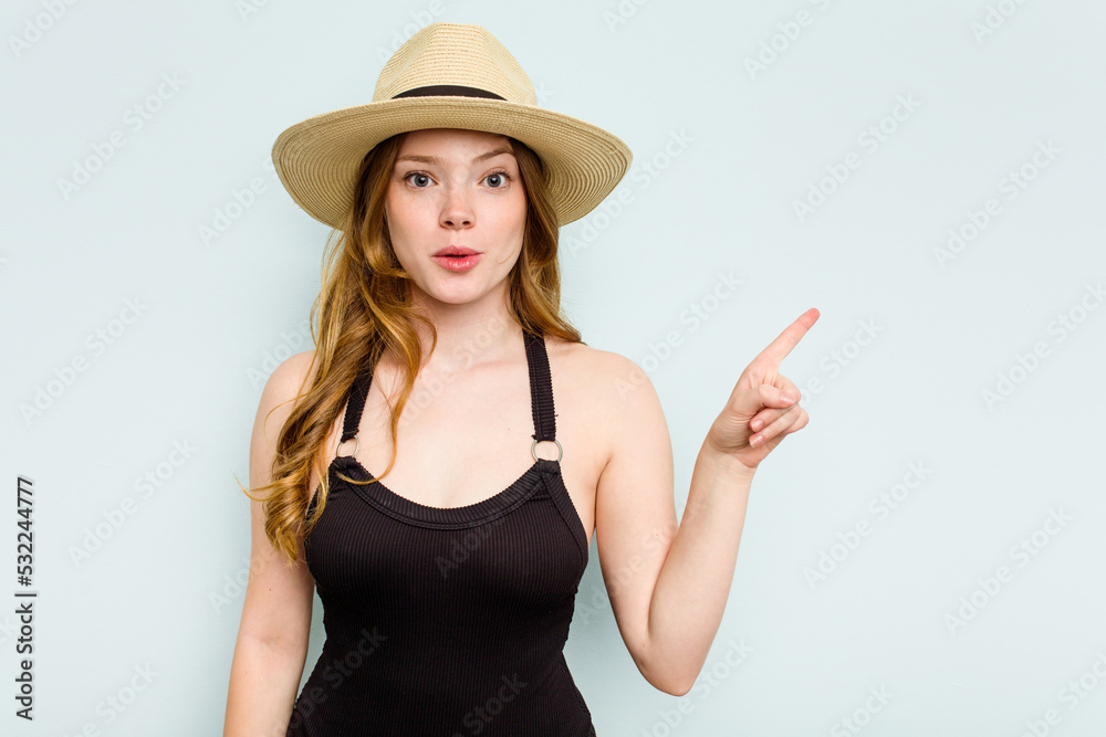 Young caucasian woman going to the beach isolated on blue background pointing to the side Young caucasian woman going to the beach isolated on blue background pointing to the side