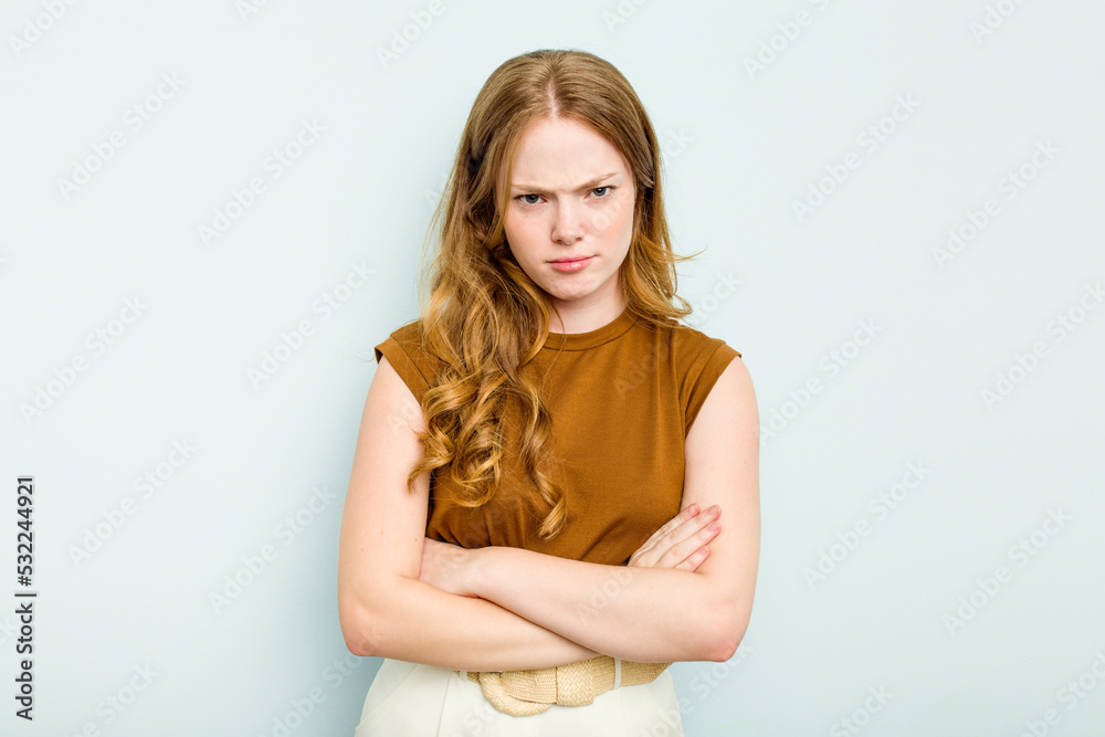 Young caucasian woman isolated on blue background frowning face in displeasure, keeps arms folded. Young caucasian woman isolated on blue background frowning face in displeasure, keeps arms folded.