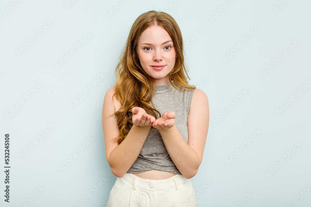 Young caucasian woman isolated on blue background holding something with palms, offering to camera. Young caucasian woman isolated on blue background holding something with palms, offering to camera.