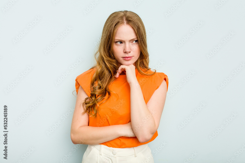 Young caucasian woman isolated on blue background suspicious, uncertain, examining you. Young caucasian woman isolated on blue background suspicious, uncertain, examining you.