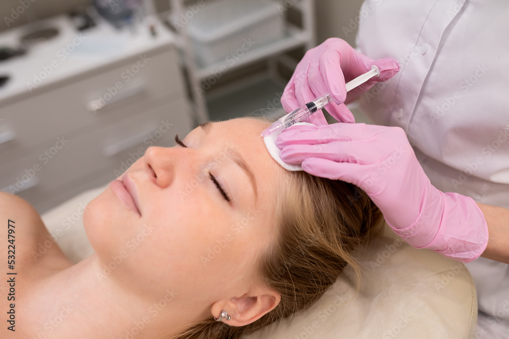 Naklejka premium Cosmetologist makes injections on the face. Spa concept relaxation and self-care.