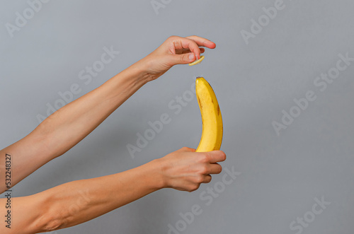Slim female hands with banana and condom. Protected sex symbol.