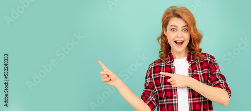 Foto amazed redhead woman in checkered shirt point finger on blue background