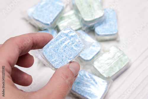 A hand holding and showing a dishwasher, dishwashing machine tablet photo