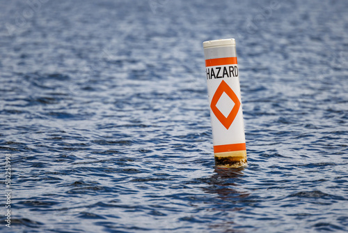 Hazard safety buoy alerting boaters to navigation danger. Nautical warning caution float.
