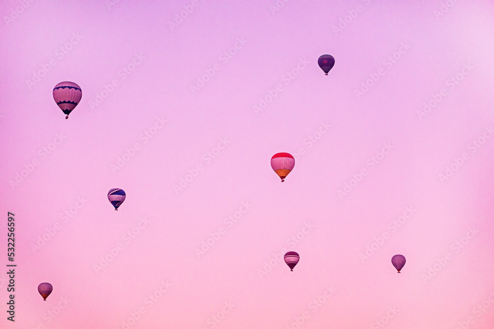 flight of hot air balloons in the pink sky before sunrise.