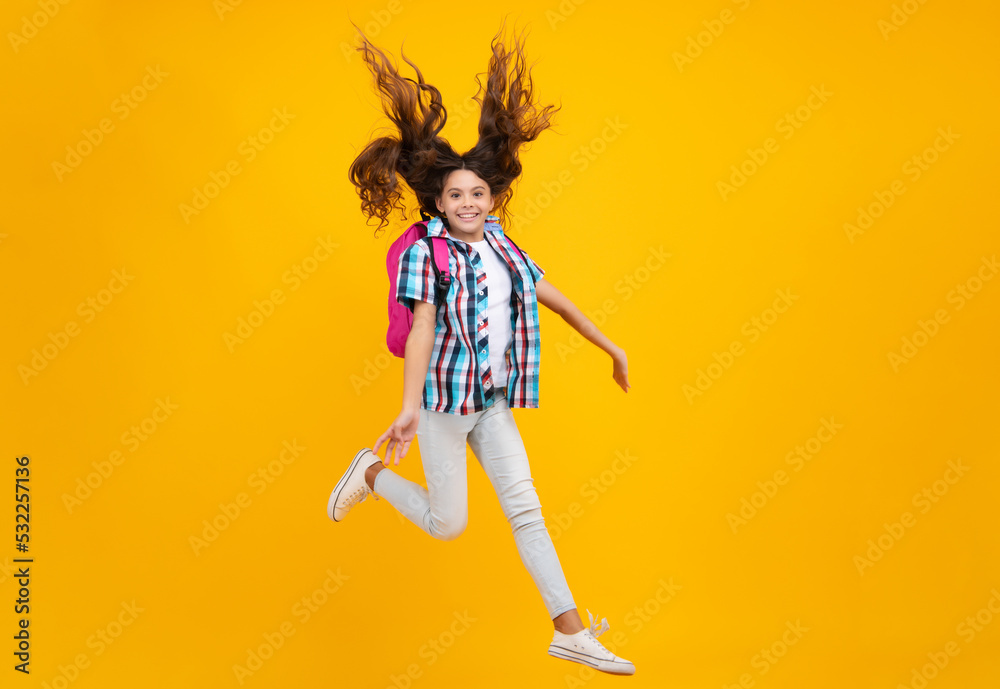 Amazed teen girl. Back to school. Teenage school girl ready to learn. School children on yellow isolated background. Run and jump. Excited expression, cheerful and glad.