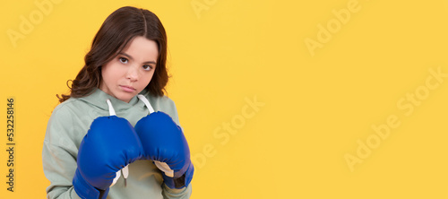 serious child portrait in boxing gloves on yellow background. Horizontal poster of isolated child face, banner header, copy space.