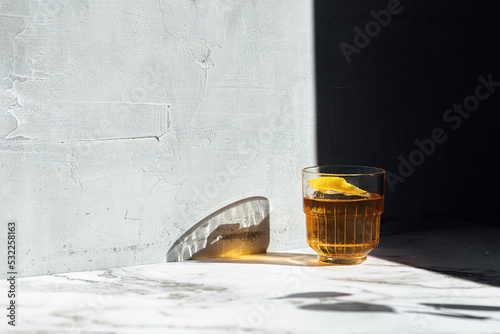 photography of whiskey cocktail glass with lemon peel as garnish with shadow
